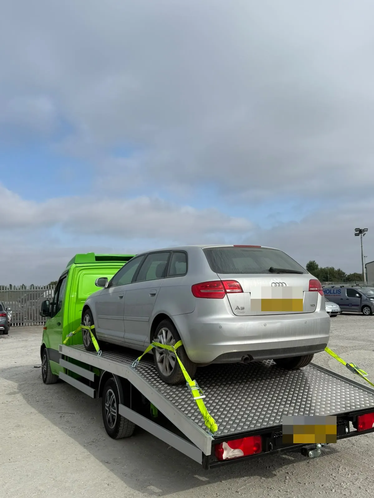 Silver Audi A3 strapped on the flatbed in a yard