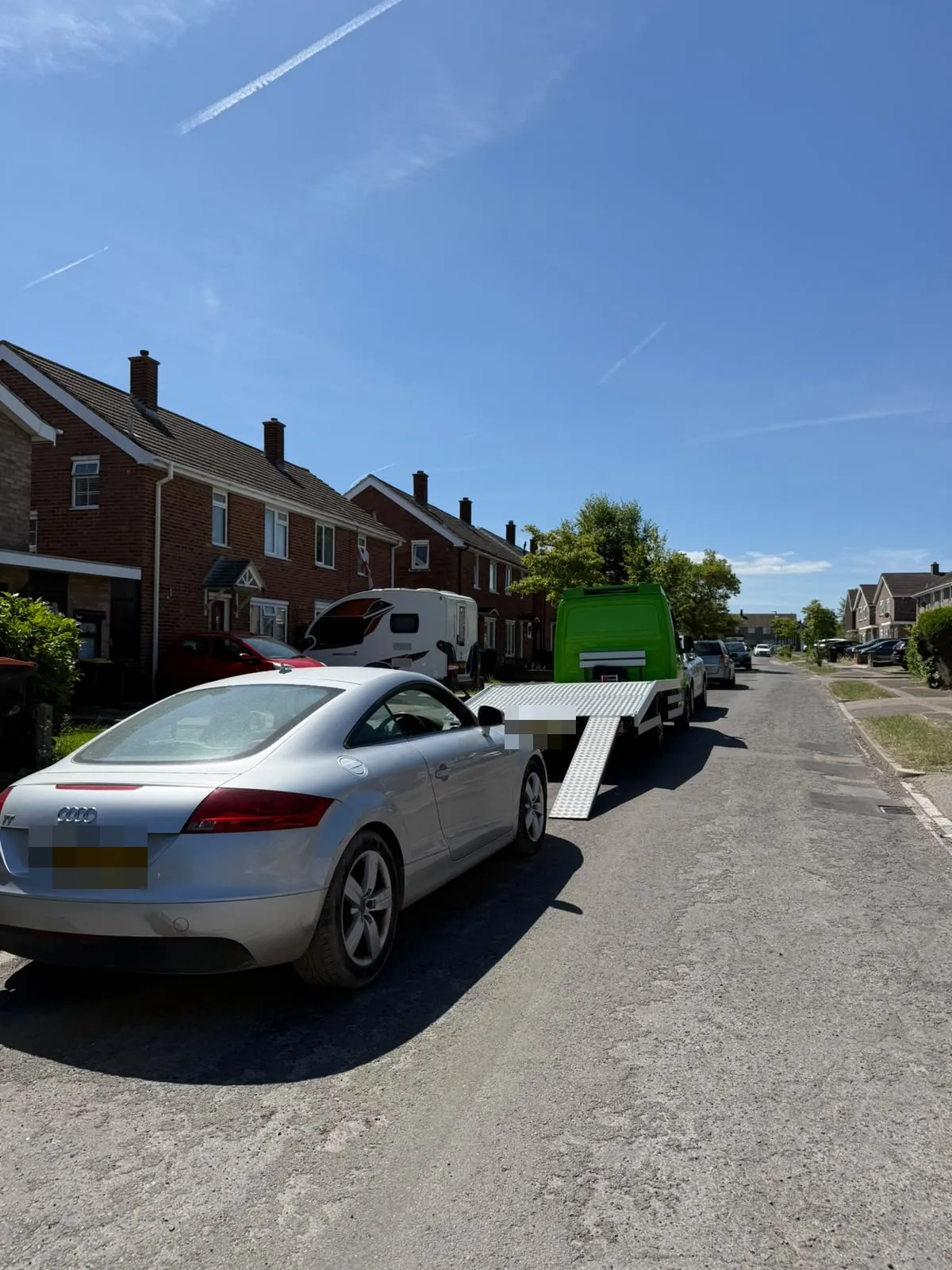 Silver Audi TT in a street with the flatbed's ramp down behind it