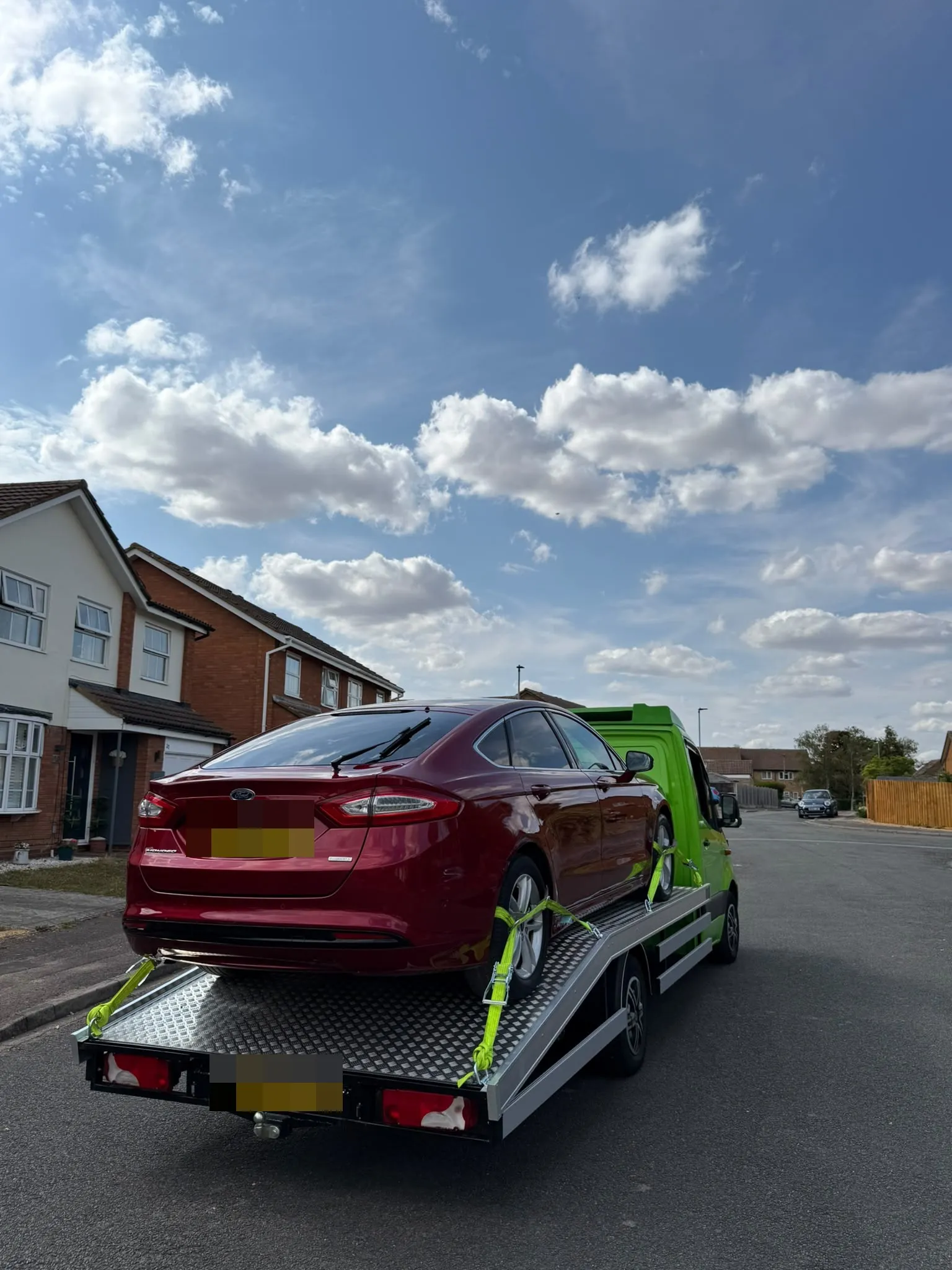 Red Ford Mondeo on the flatbed in a residential street