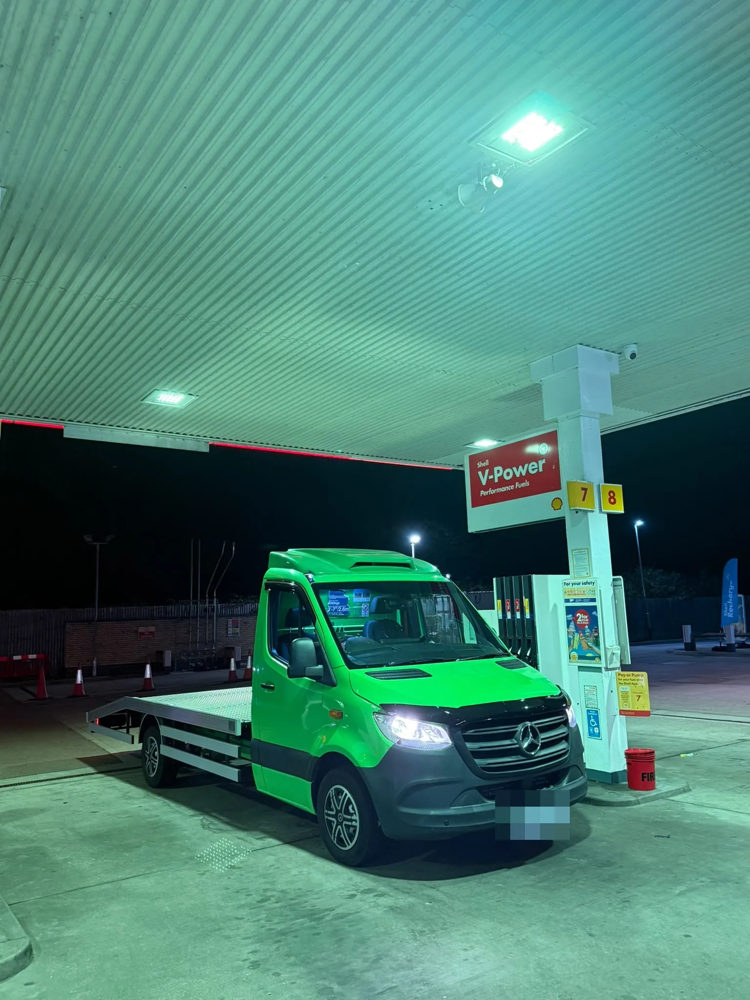The lime green flatbed truck lit up at a petrol station at night