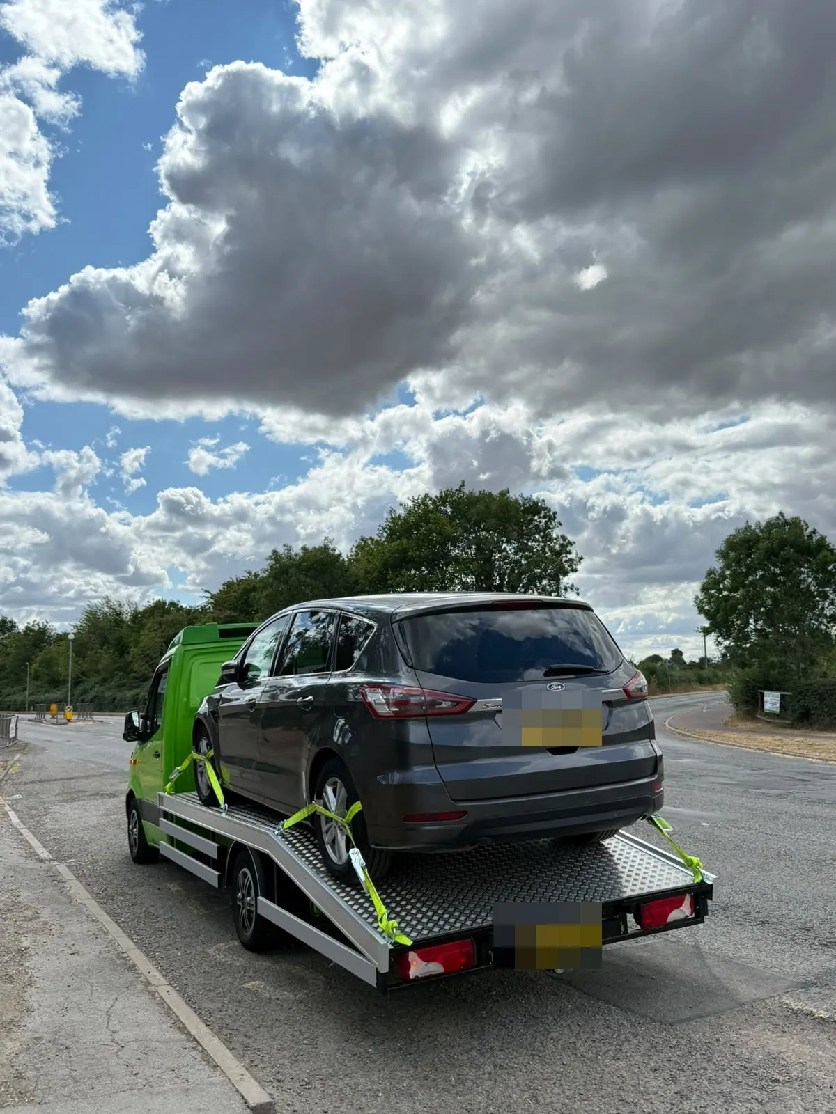 Grey Ford S-Max strapped on the flatbed by a main road